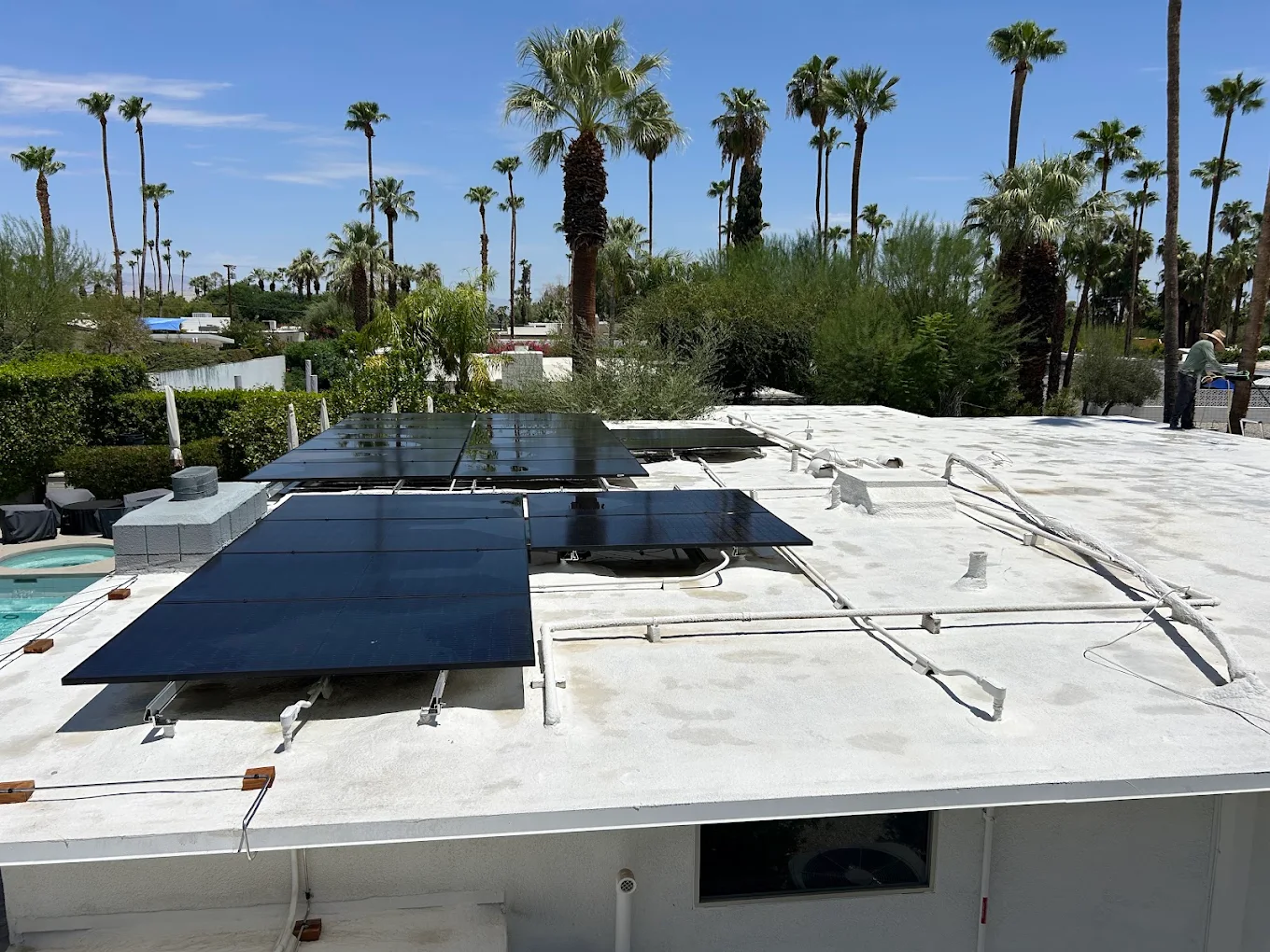 Glossy technician cleaning rooftop solar panels in the Coachella Valley